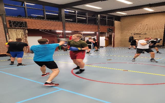 Leden oefenen in tweetallen tijdens de bokstraining